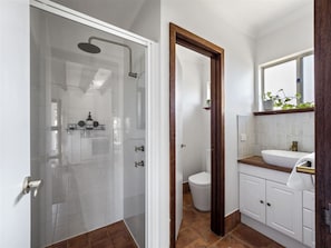 A modern bathroom with a glass-enclosed shower, a white toilet, and a wooden vanity with a sink. - Cottage at Dunmore Homestead | Peaceful Retreat (Scott River East)