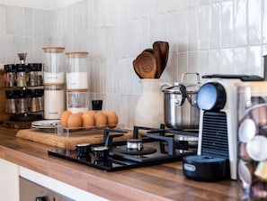 A kitchen with a gas stove, a coffee maker, and various kitchen utensils.