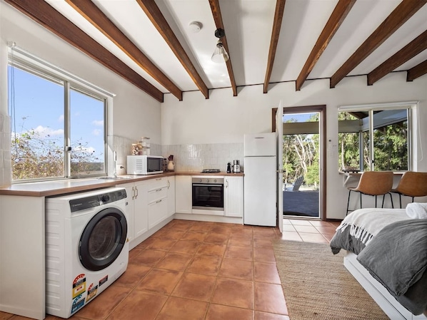 A compact kitchen with a washing machine, oven, and dining area with chairs.