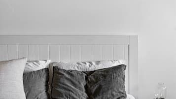 Une chambre à coucher avec un lit, des oreillers, une table de chevet avec une lampe et un tableau encadré au mur.
