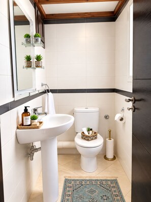 Ein Badezimmer mit einem weißen Waschbecken, einer Toilette und einem dekorativen Teppich.