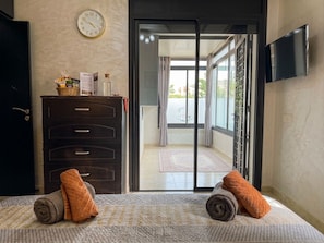 Ein Hotelzimmer mit Bett, Schminktisch, Fernseher und Blick ins Freie.