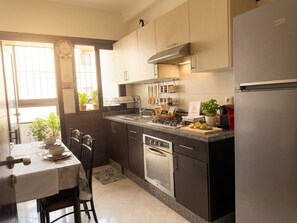 Eine moderne Küche mit Einbauofen, Edelstahlkühlschrank und einem Essbereich mit Tisch und Stühlen.