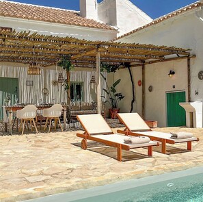 A poolside area with lounge chairs and a dining table. - Andalusian farmhouse amid olive groves, Iznájar (Iznájar)