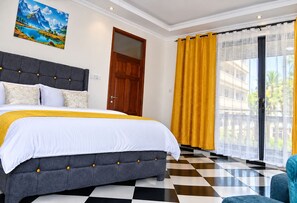 A hotel room with a large bed, a view of the outside, a wooden door, and a checkered floor. - The Coastal Nest Diani Beach (Diani Beach)