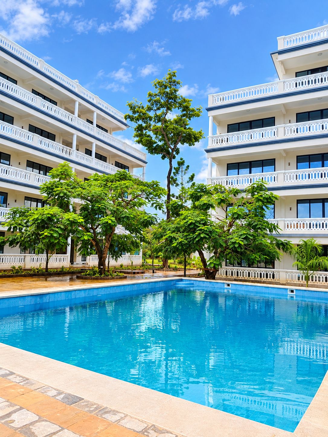 A swimming pool with a clear blue sky, surrounded by multi-story buildings with balconies.