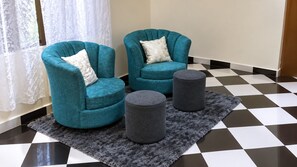 Una habitación con dos sillones color turquesa, una alfombra gris y un suelo a cuadros.