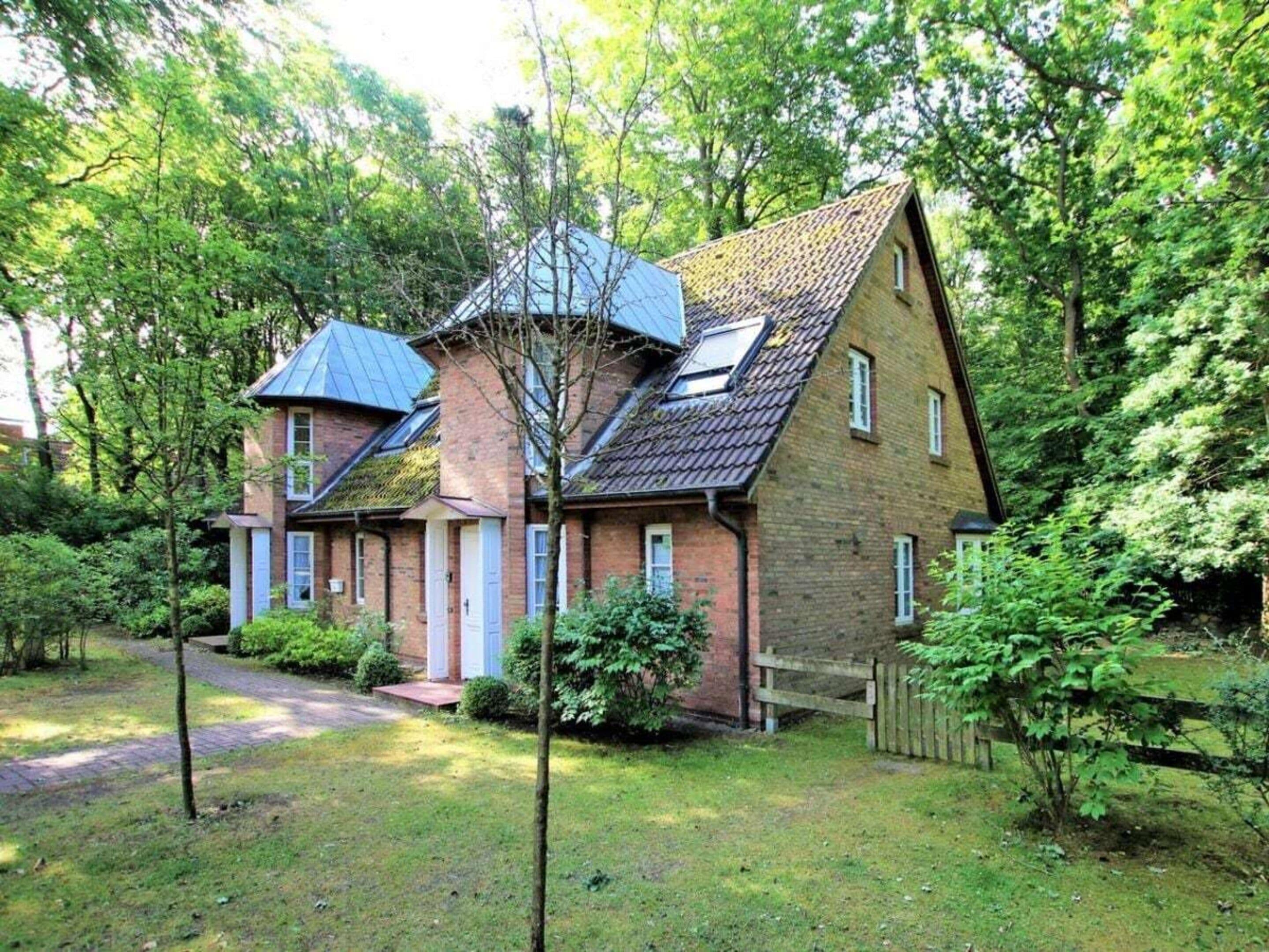 Une maison à deux étages avec un toit en pente, une cheminée bien visible et un porche à l’avant.