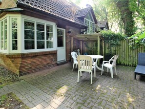 Ein Backsteinhaus mit überdachter Terrasse, komplett mit Tisch und Stühlen.