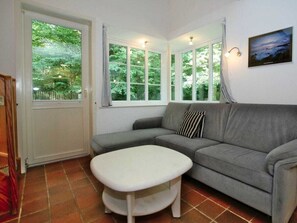 A living room with a grey sofa, a white ottoman, and a window with curtains. - Gmelinstrasse 19 d (Wyk auf Foehr)