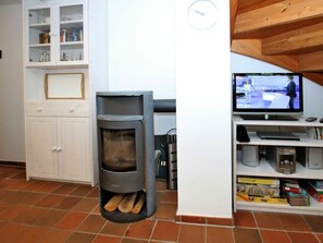 A room with a built-in wood stove, a television, and a bookshelf with books and DVDs. - Gmelinstrasse 19 d (Wyk auf Foehr)