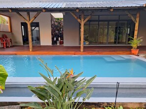 Ein Schwimmbecken mit Holzterrasse und überdachter Veranda.
