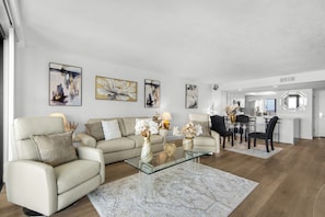 A modern living room with a sofa, coffee table, and artwork on the walls. - Edgewater Beach Condo 505 (Destin)