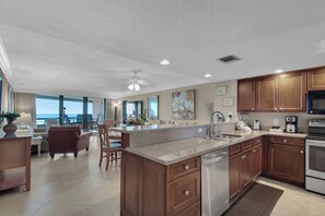A modern kitchen with granite countertops, stainless steel appliances, and wooden cabinets. - Edgewater Beach Condo 0603 (Destin)