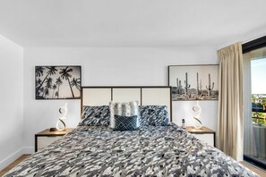 A modern hotel room with a large bed, two bedside tables, a headboard, and two framed pictures on the wall. - Edgewater Beach Condo 608 (Destin)