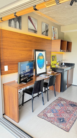 Een knus woongedeelte met een kitchenette, een eethoek met een televisie en een klein vloerkleed.