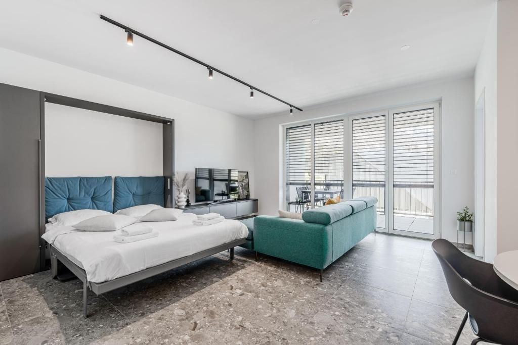 Un dormitorio moderno con cama, sofá, escritorio y un ventanal con persianas.