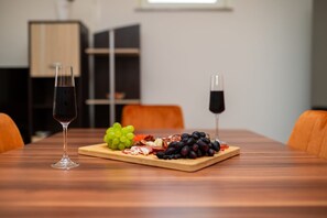 A wooden table with a glass of red wine, a glass of black wine, and a wooden board with grapes, cheese, and meat. - Casa delle Rondini in Belej (Belej)