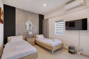 A hotel room with two beds, a flat-screen TV, a mirror, and a modern design. - Beautiful, private 3BR Sliema House w/Roof Terrace (Sliema)