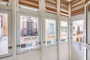A corridor with multiple doors leading to balconies with views of a residential area. - Beautiful, private 3BR Sliema House w/Roof Terrace (Sliema)