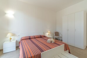 A simple, clean room with a bed, two bedside tables with lamps, a chair, and a wardrobe. - Apartment 'Lungomare Avola  with Sea' with Balcony, Wi-Fi and Air Conditioning (Avola)