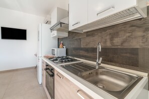 A modern kitchen with a stainless steel sink, a gas stove, and white cabinetry. - Apartment 'Lungomare Avola  with Sea' with Balcony, Wi-Fi and Air Conditioning (Avola)