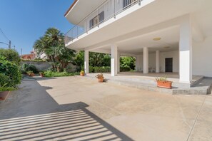 A modern building with a covered outdoor area, columns, and potted plants. - Apartment 'Lungomare Avola  with Sea' with Balcony, Wi-Fi and Air Conditioning (Avola)