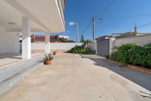 A residential area with a paved driveway, a white building with a balcony, and a gated entrance. - Apartment 'Lungomare Avola  with Sea' with Balcony, Wi-Fi and Air Conditioning (Avola)