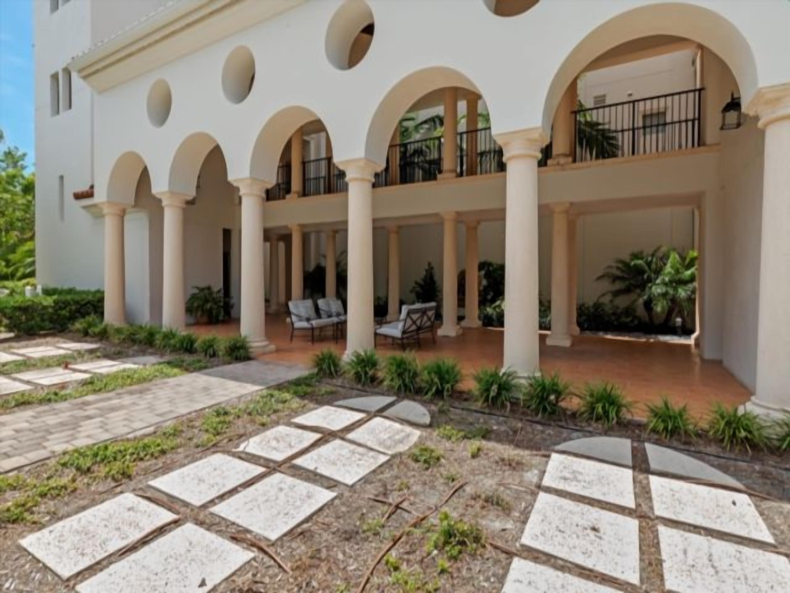 A building with a covered courtyard, columns, and outdoor seating.