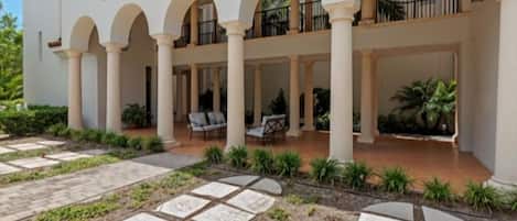A building with a covered courtyard, columns, and outdoor seating.