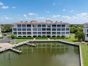 Un edificio de varios pisos con una piscina rectangular al frente.