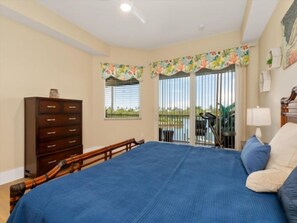 Un dormitorio con una cama grande, un aparador, una ventana con cortinas y un balcón.