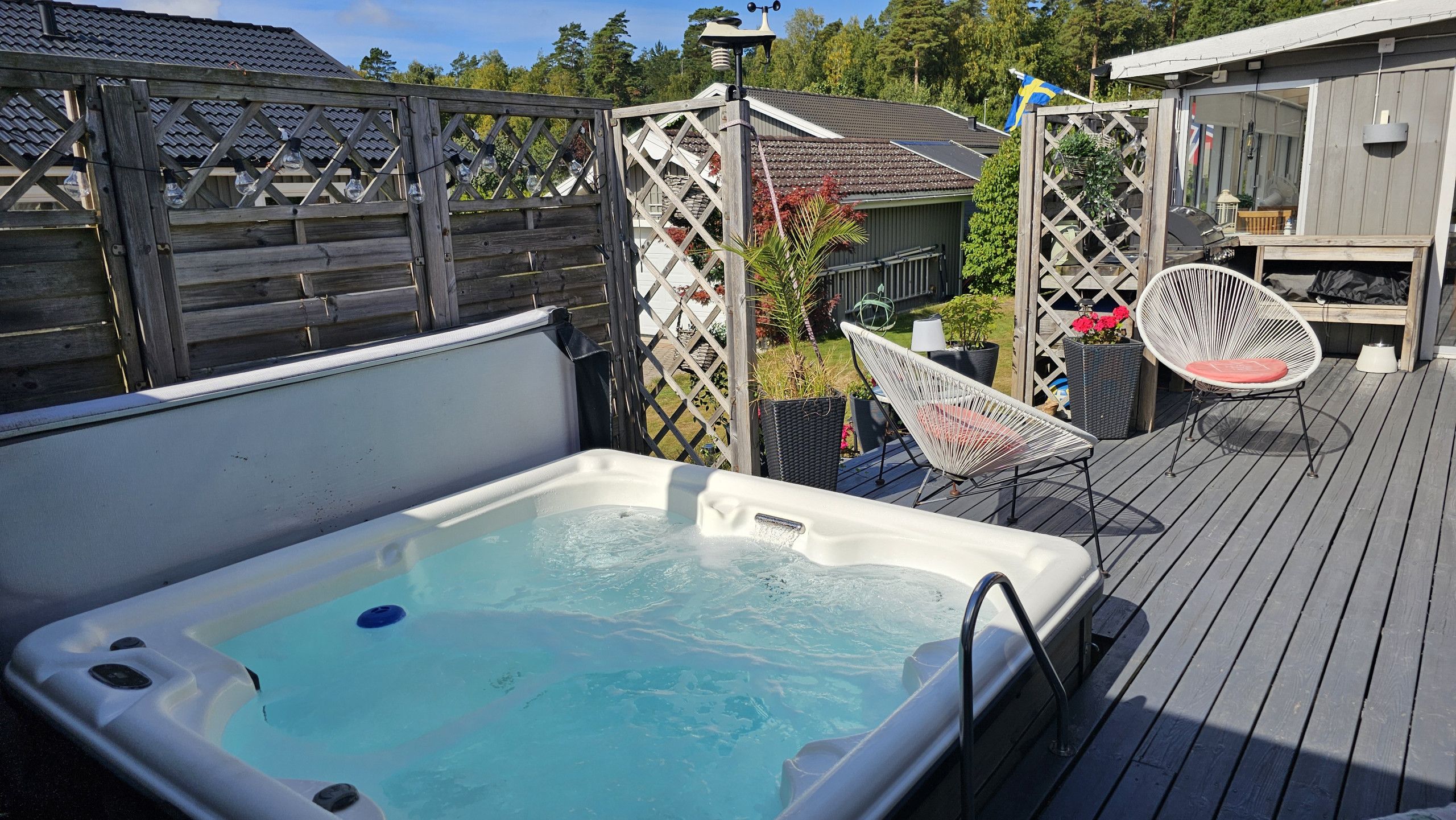 Ett bubbelbad på ett trädäck med utomhusmöbler och ett staket.