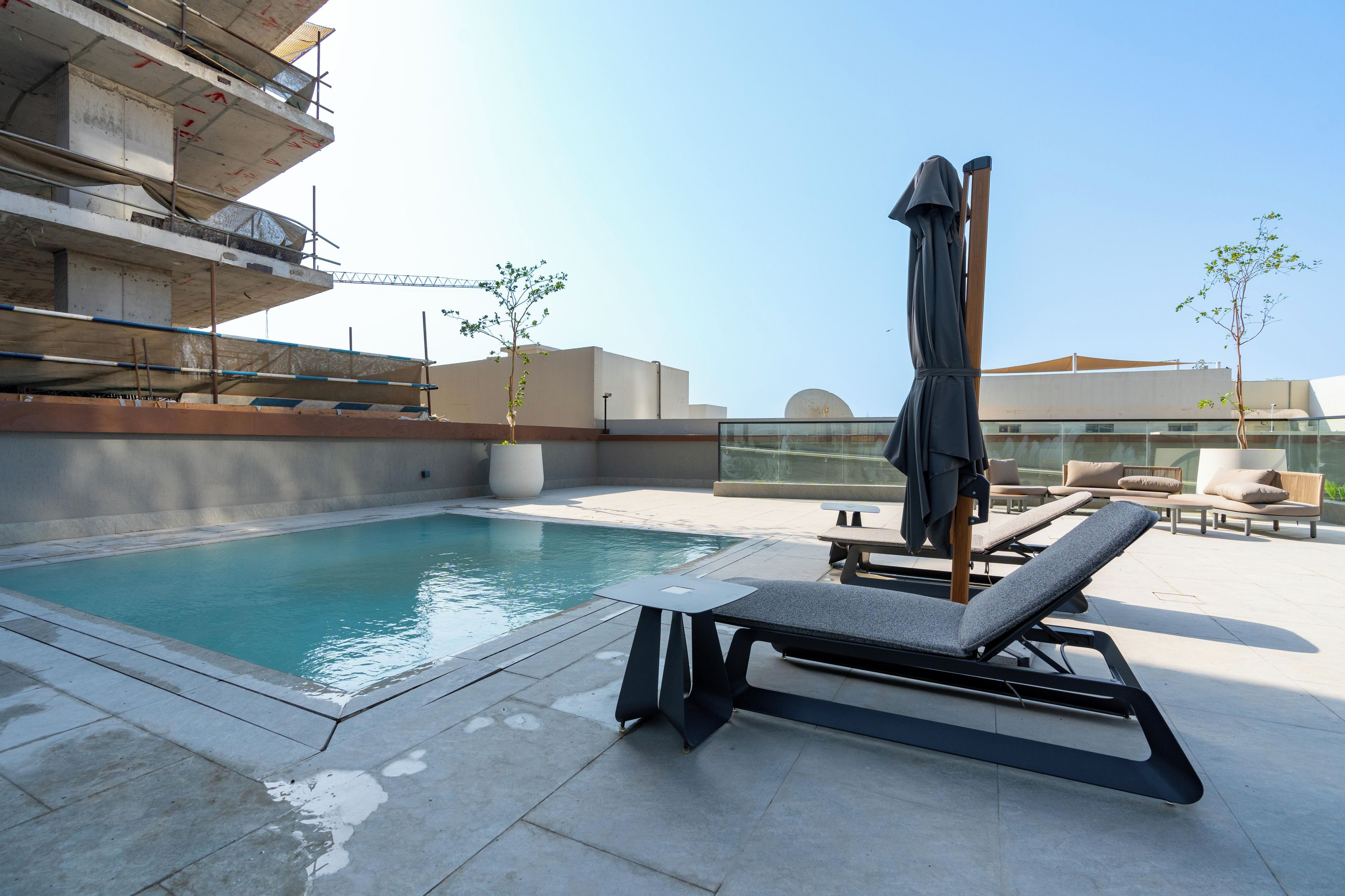 Un área de piscina en la azotea con sillones de descanso y una zona de estar techada.