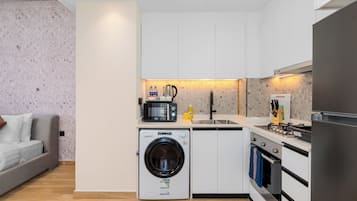 Cocina compacta equipada con lavadora, microondas y estufa.