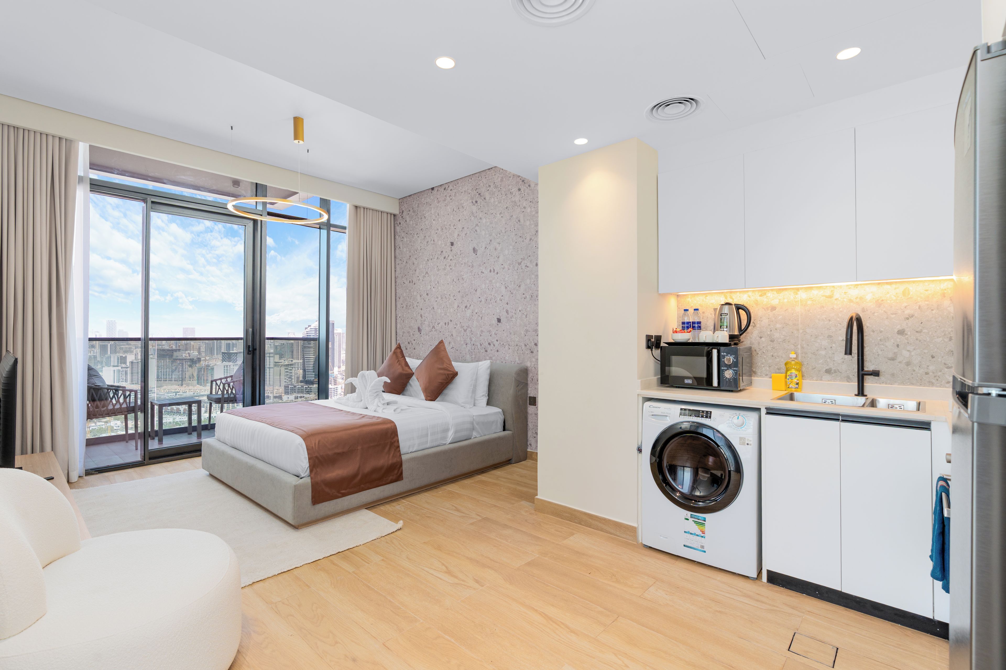 Una habitación de hotel moderna con una cama grande, lavadora y kitchenette.