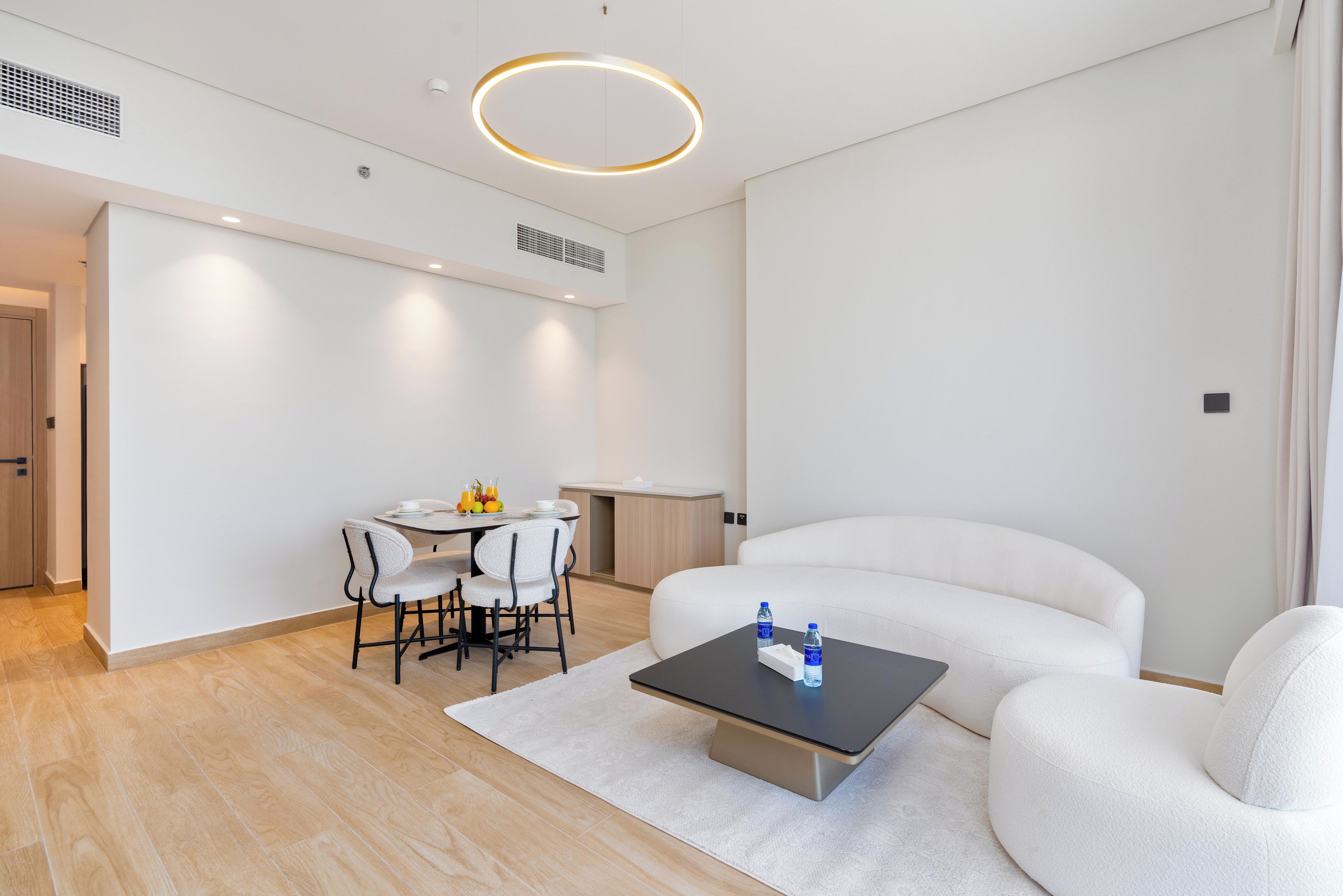 A modern hotel room with a dining area, a sofa, and a coffee table.