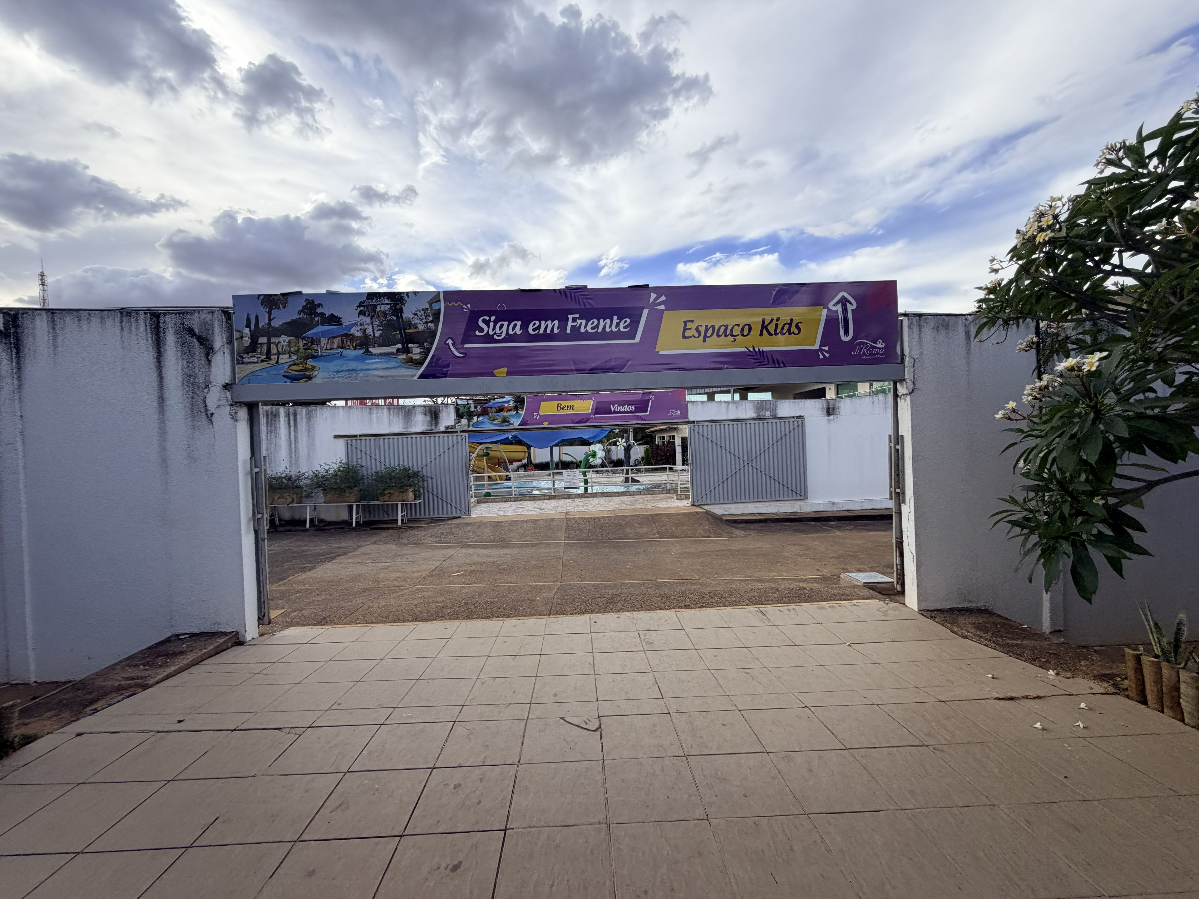 A gated entrance to a park with a sign reading 'Siga em Frente Espaço Kids'.