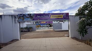 A gated entrance to a park with a sign reading 'Siga em Frente Espaço Kids'.