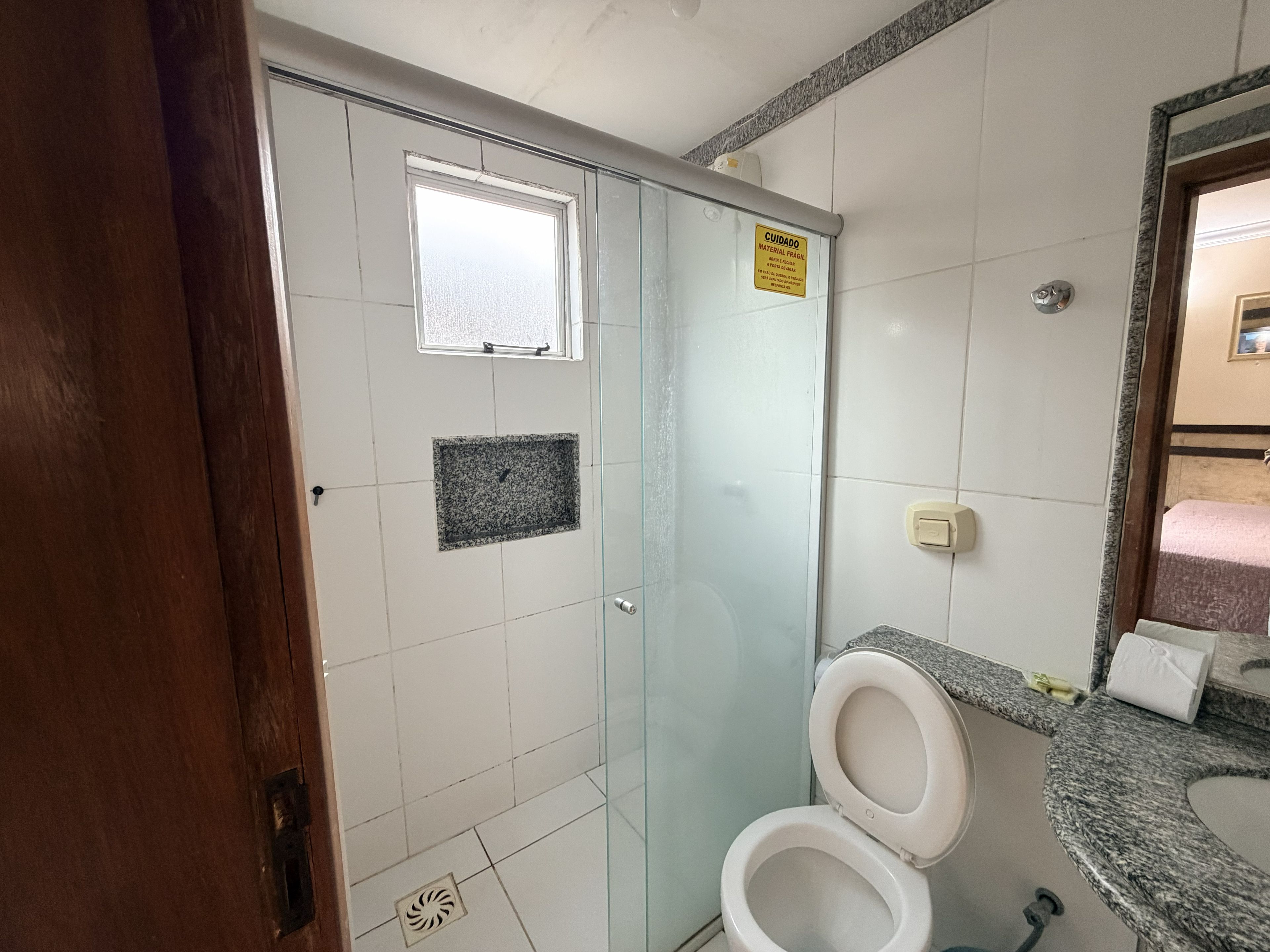A bathroom with a toilet, a shower, and a sink.