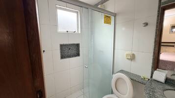 A bathroom with a toilet, a shower, and a sink.