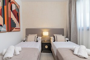 Ein Hotelzimmer mit zwei Betten, einem Nachttisch mit Lampe und einem Gemälde an der Wand.