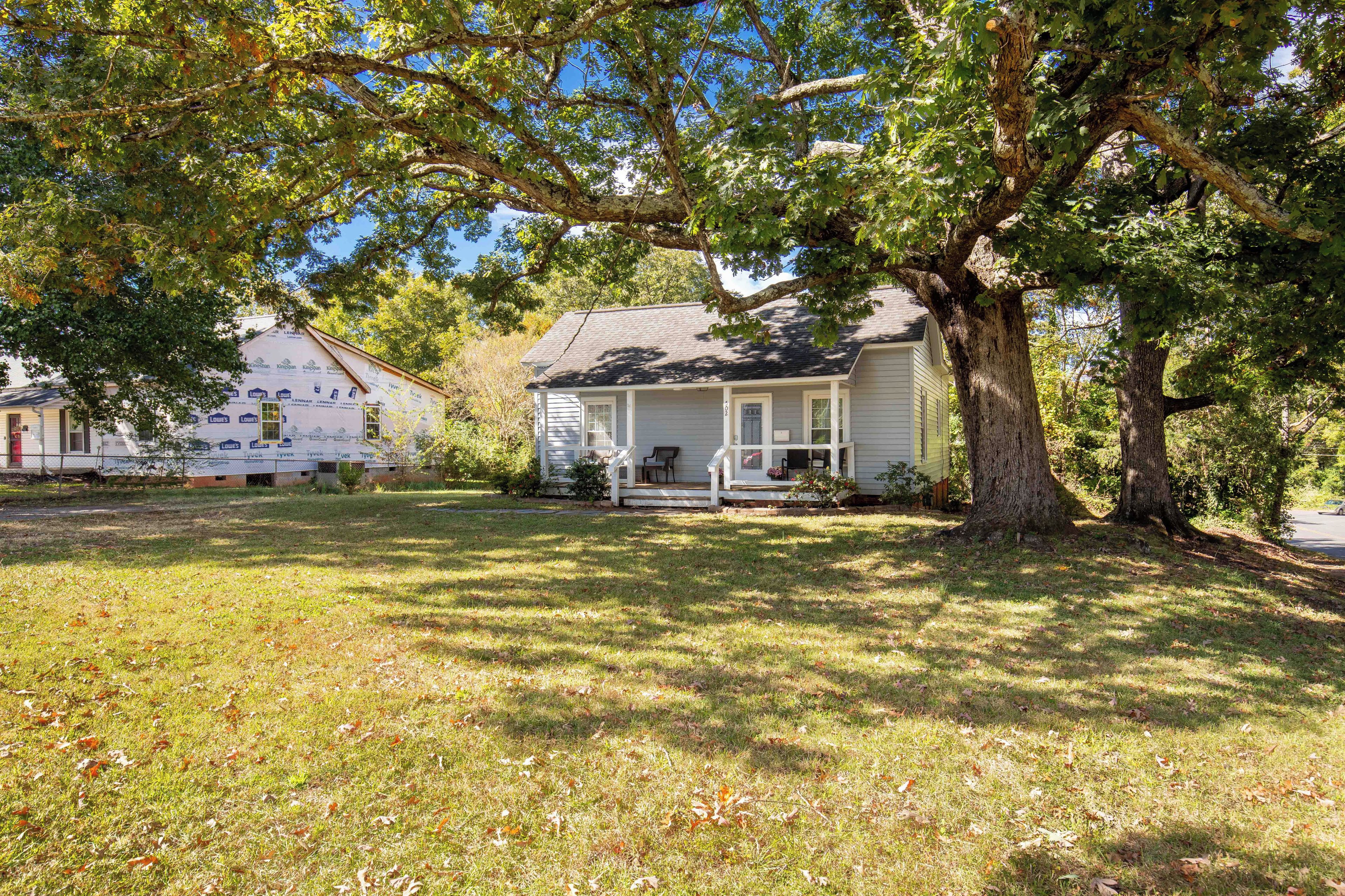 A residential area with houses, a large tree, and a grassy lawn.