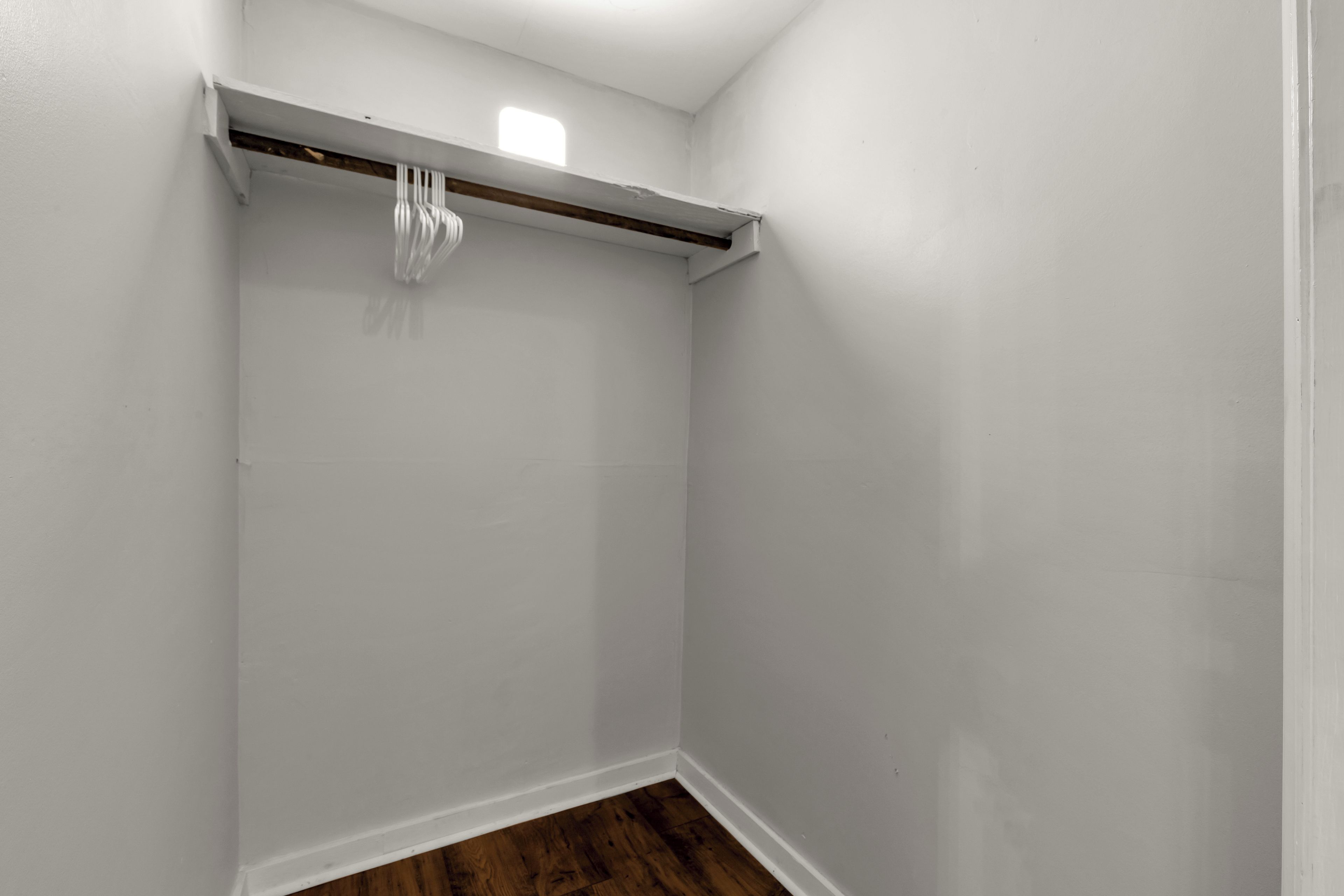 A corner of a room with white walls and a wooden floor.