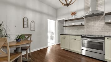 A modern kitchen with wooden flooring, stainless steel appliances, and a white brick backsplash.