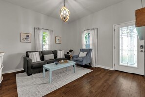 Una sala de estar con sofá, sillón, mesa de centro y una araña.