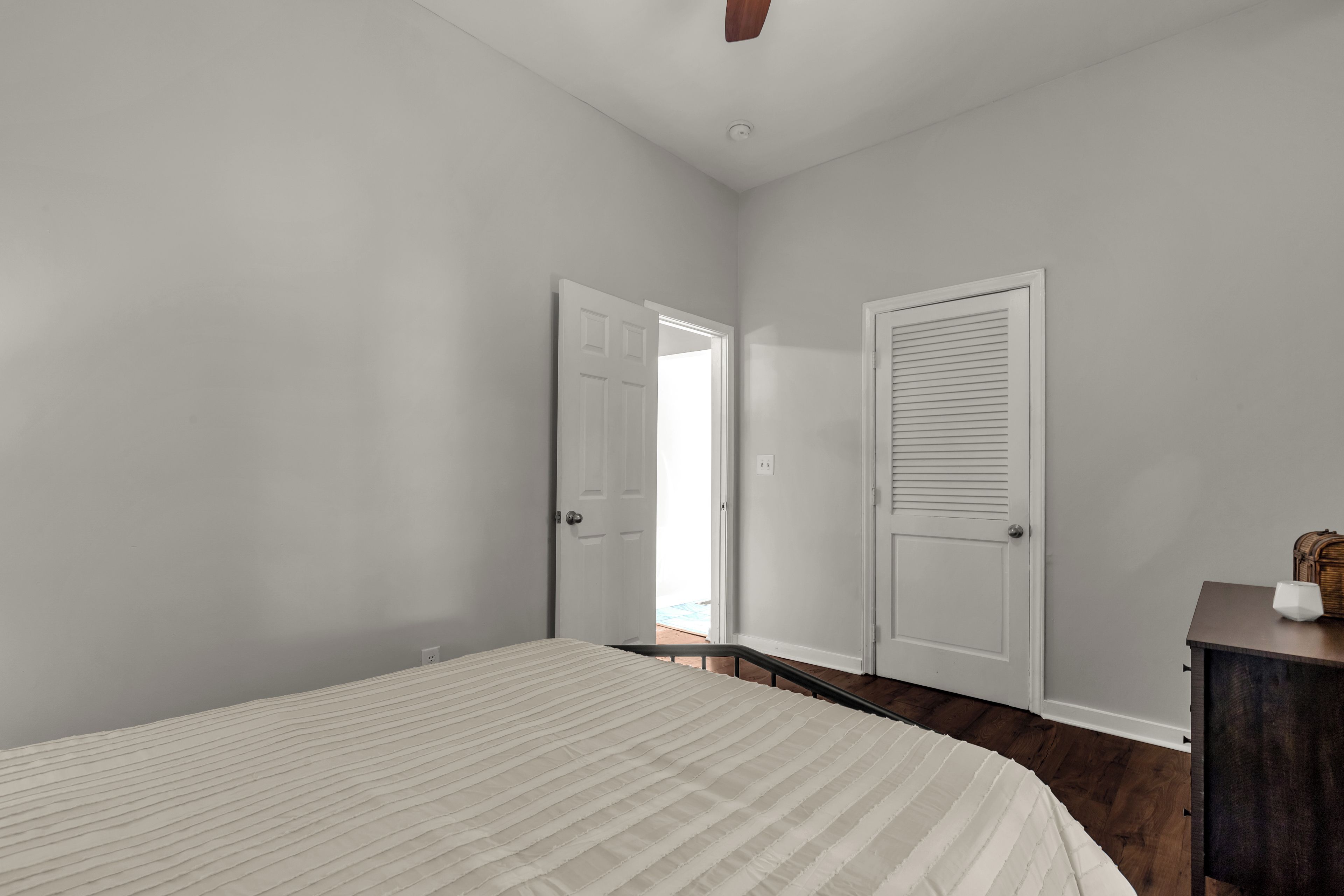 A bedroom with a bed, a dresser, and two doors.