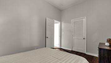 A bedroom with a bed, a dresser, and two doors.
