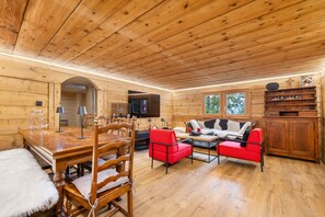 A wooden interior with a dining table, chairs, a sofa, and a television. - Laetitia Chalet - Sleeps 8 - Charm and Authenticity (Haute-Nendaz)