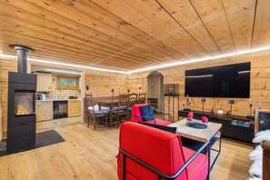 A cozy wooden interior with a dining area, a TV, and a fireplace. - Laetitia Chalet - Sleeps 8 - Charm and Authenticity (Haute-Nendaz)